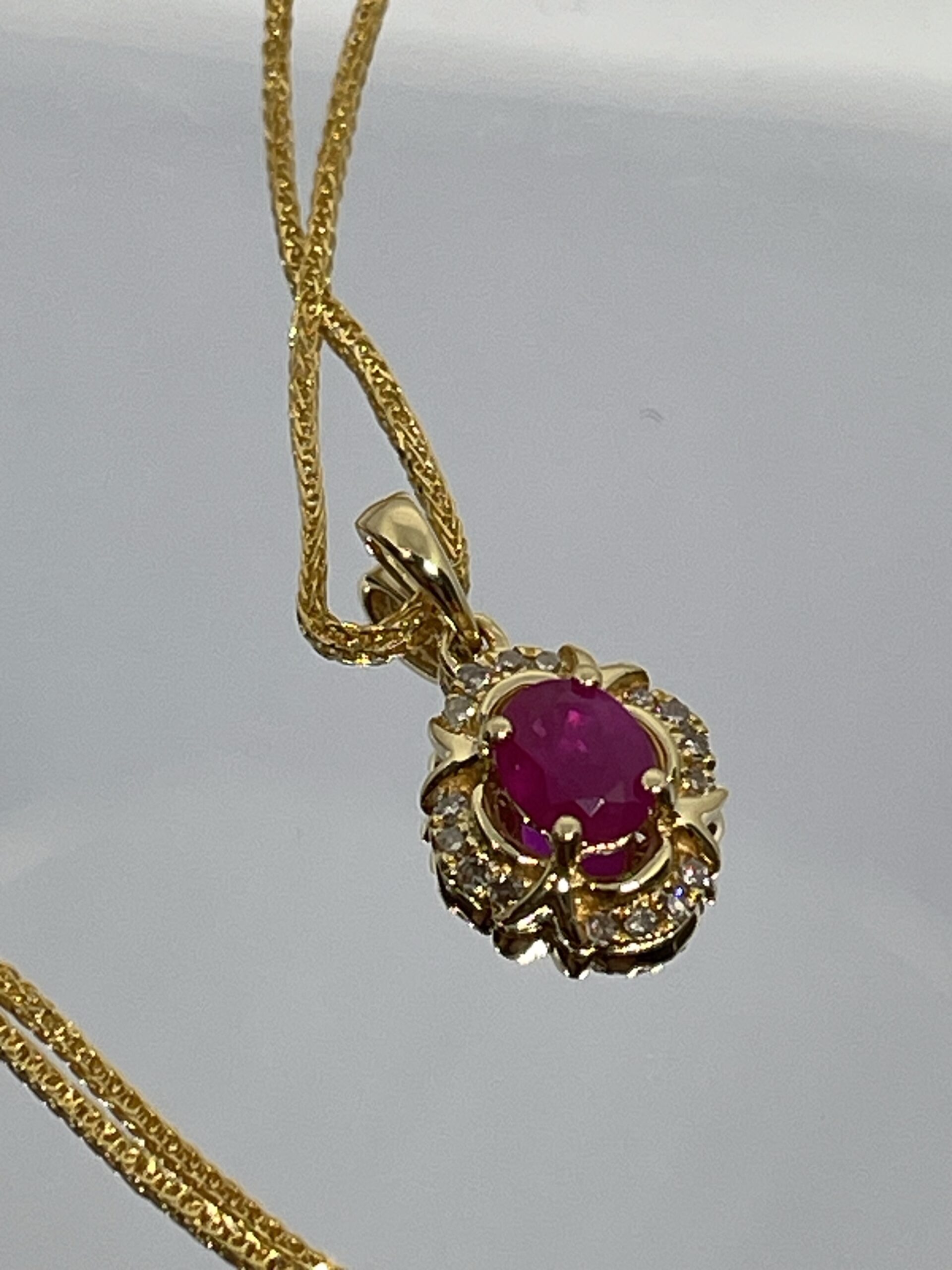 Colgante de Oro con Rubí Oval y Halo de Diamantes Champagne
